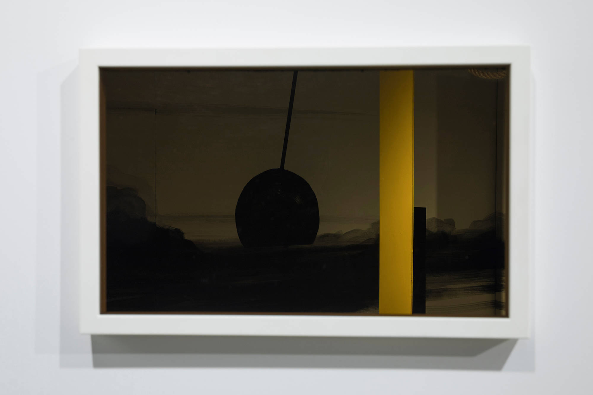 Image of a frame hung on a wall with tinted glass disguising a window into an installation behind the wall, showing a yellow column and a black circle like a clock's weight.