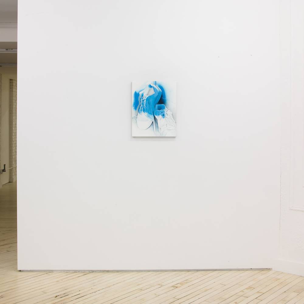 Installation view of a small vertical painting on a white wall with a hallway on the left side of the wall.