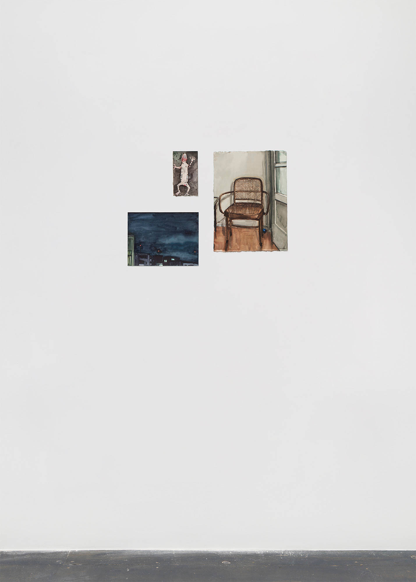 Three watercolor paintings on paper are hung on a white wall above a grey floor. Clockwise, they depict a lizard, a wicker chair, and a cityscape at night.