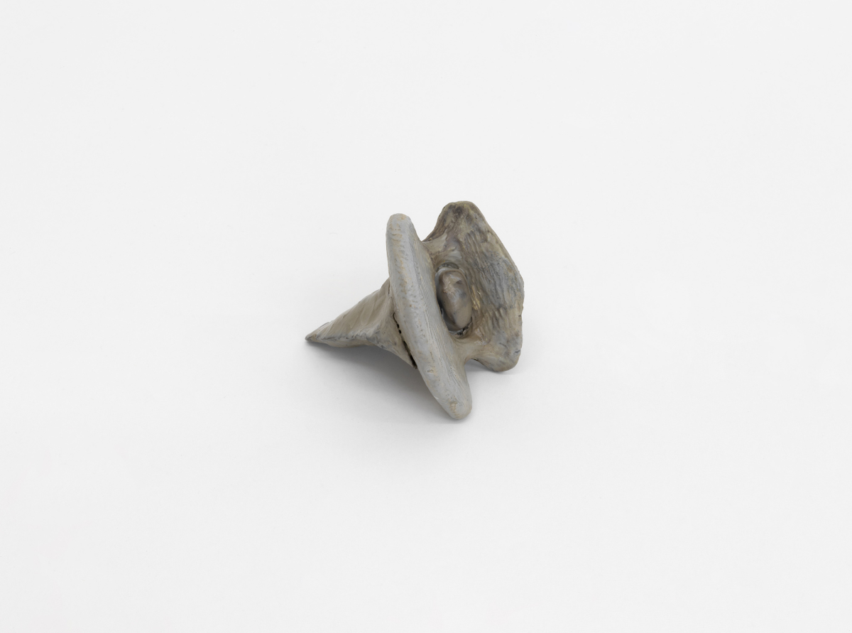 A small abstract sculpture resembling organic material . It is gray. 