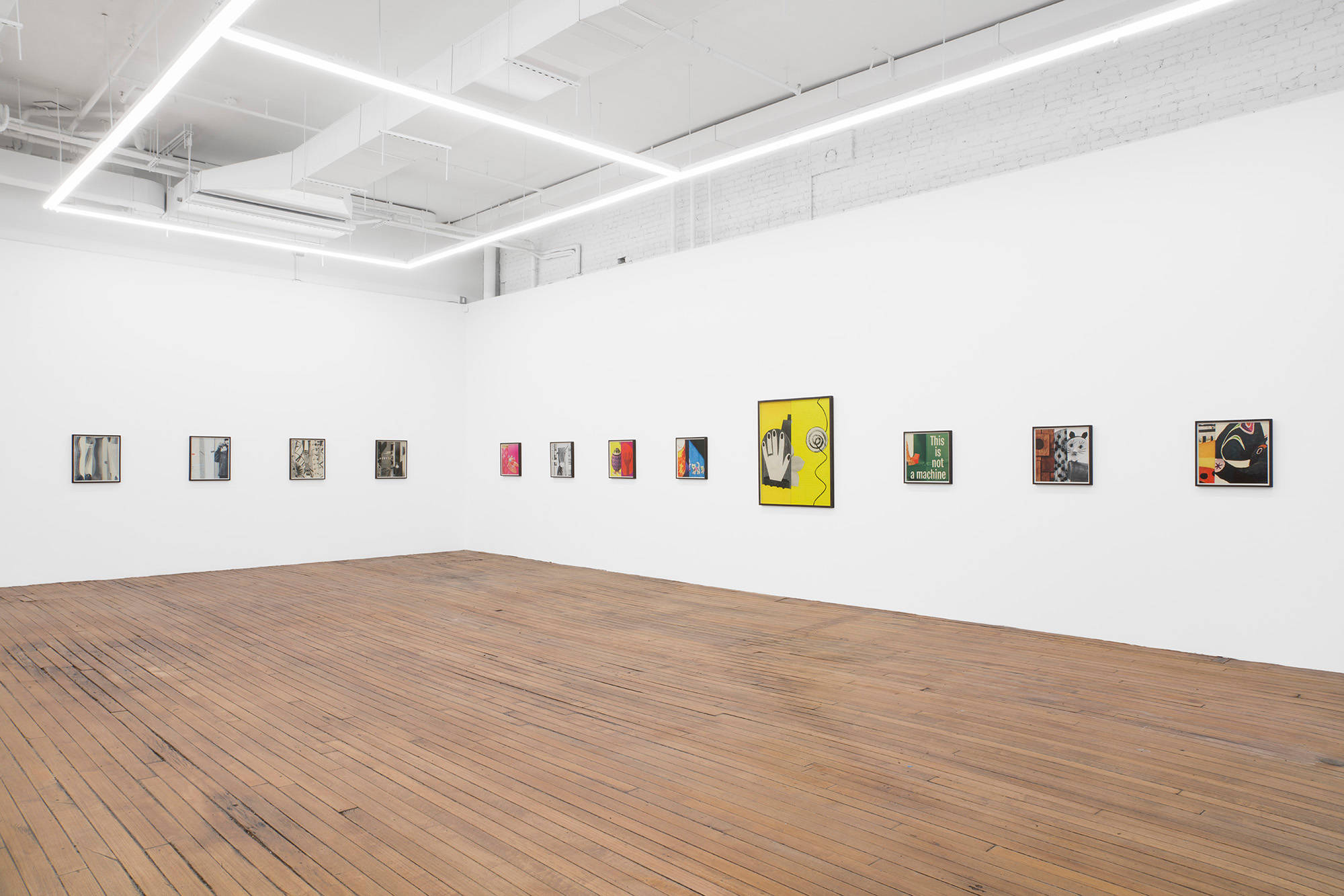 A large gallery space filled with evenly spaced colorful photographs in dark brown frames.