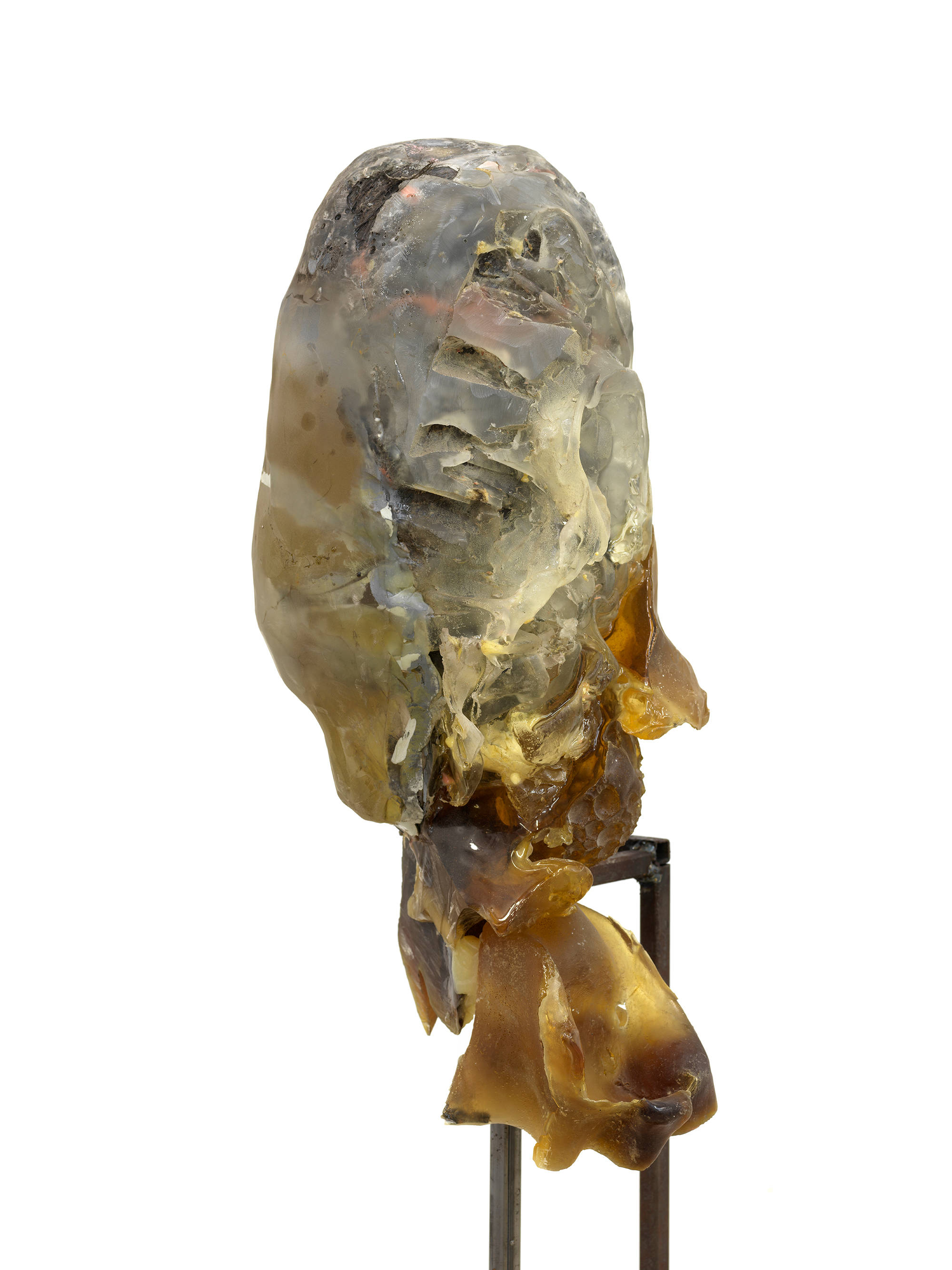 In a gallery space, a detail of an abstract sculpture resembling a human form with a steal base.