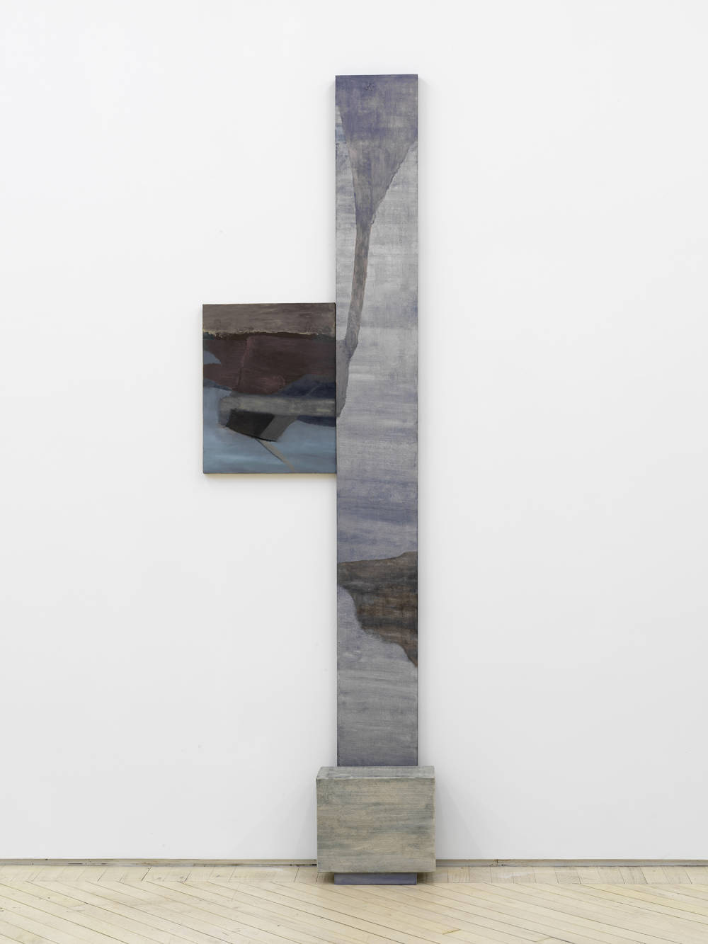 A vertical, abstract painting and sculpture leaning against a gallery wall.