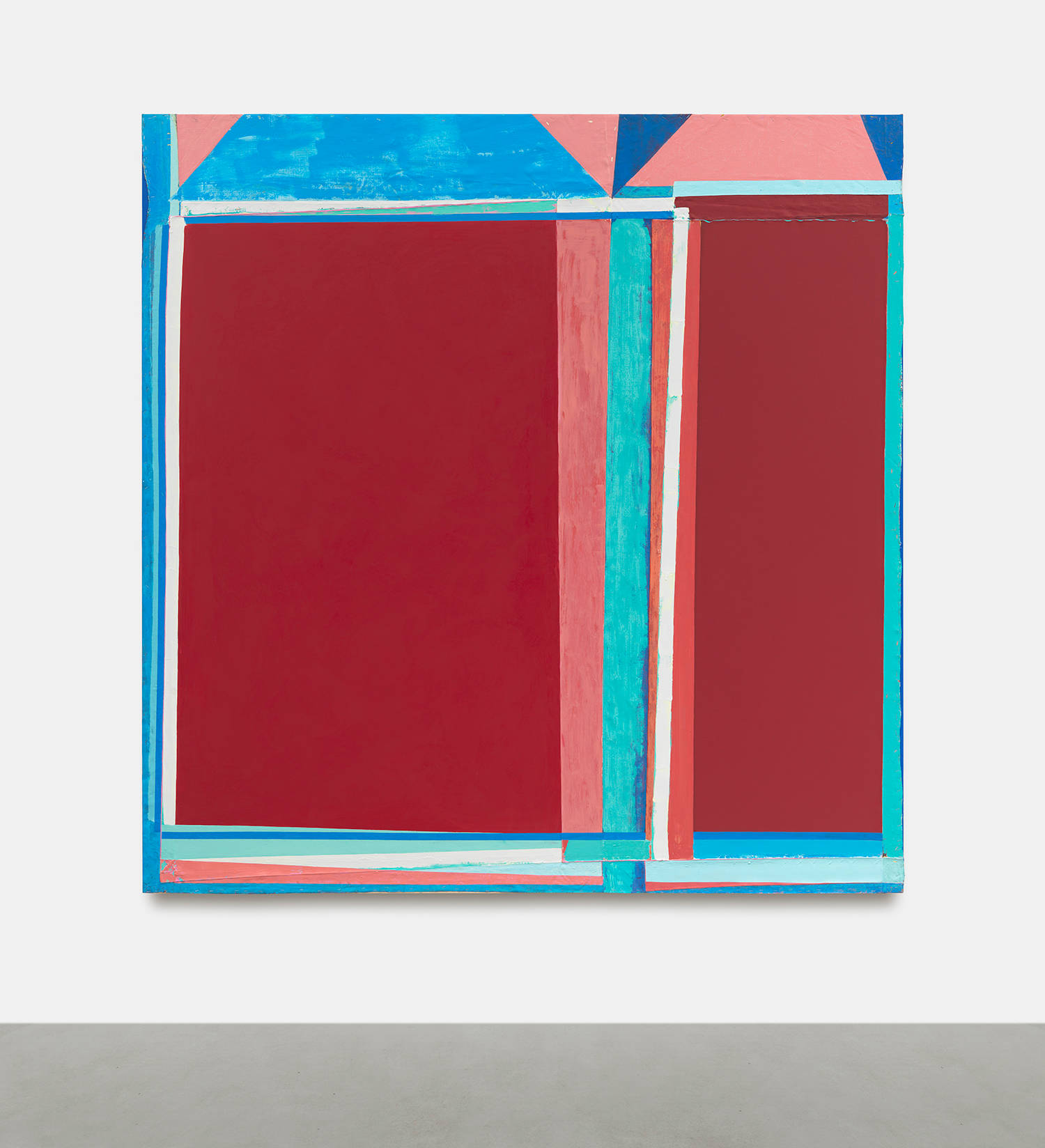 A large abstract painting on a white wall with gray floor below. The painting is a combination of discreet abstract shapes painted in bold colors. The outstanding colors are a hue of reds, blues, pinks and greens. The paint is thick and brushy and the canvas is rough with creases.