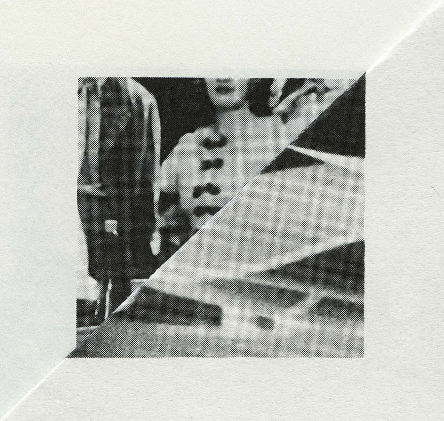 Image of the folded corner of a page of a book, with a central square made up of two black and white images creating two triangles due to the folding of the paper. It is unclear what the bottom triangle is depicting but the top triangle shows a cropped image of a woman and a man standing side by side.