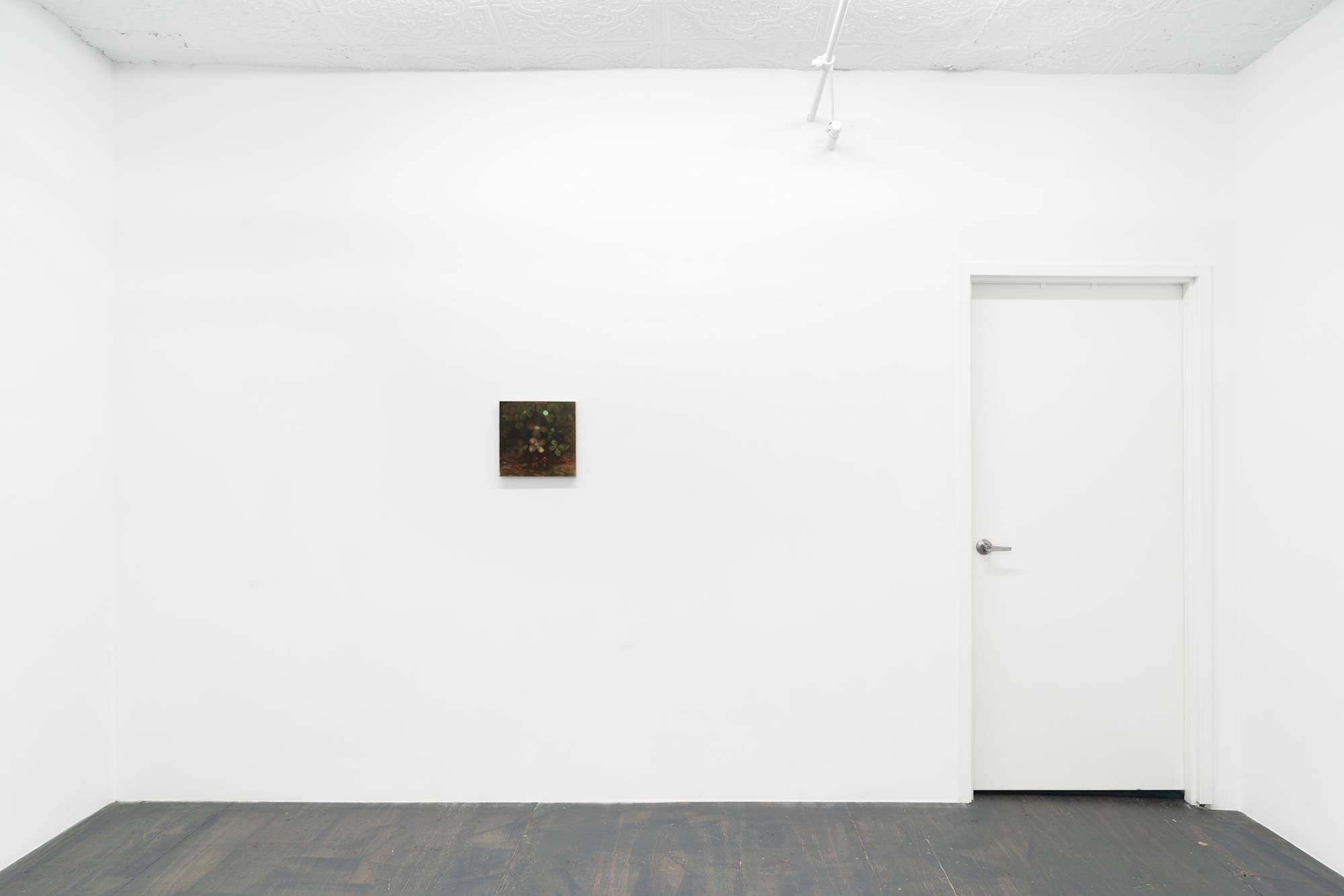 A small abstract paintings of flowers hangs on a wall to the left of a door in a brightly lit gallery space with grey wood floor.