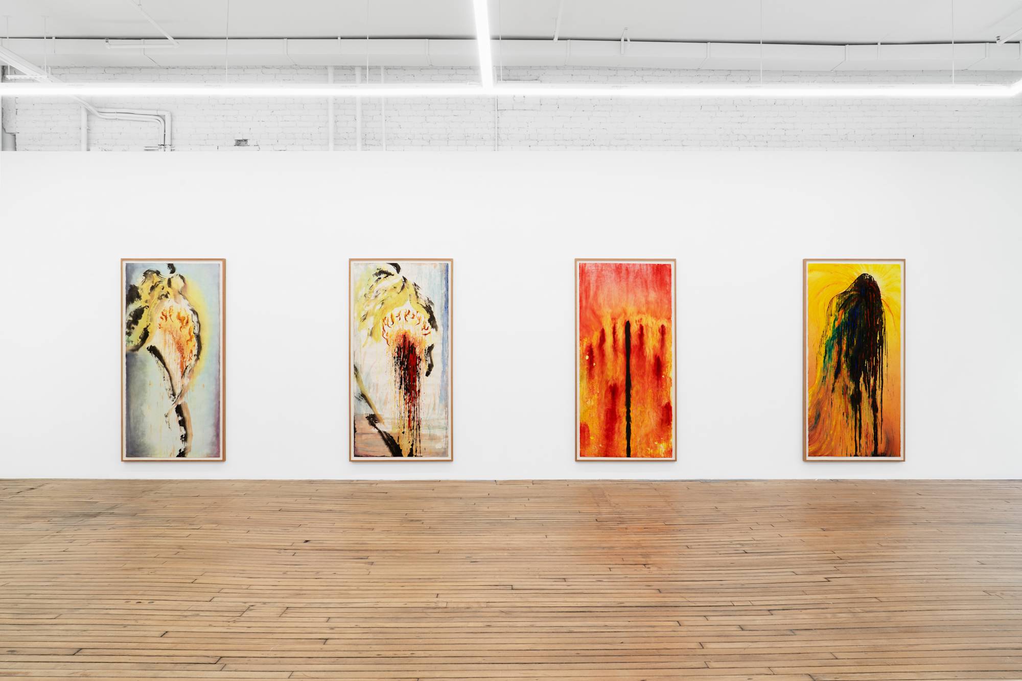 Four large ink paintings of sunflowers, some in various stages of decay, hang in a horizontal row in white-walled gallery with wooden floors. The two compositions on the left are done in green, black, yellow, orange, red, and light blue ink. The second composition from the right is predominantly dark red and orange. The first composition from the right has a central black splatter with a predominantly yellow-orange and ochre background.
