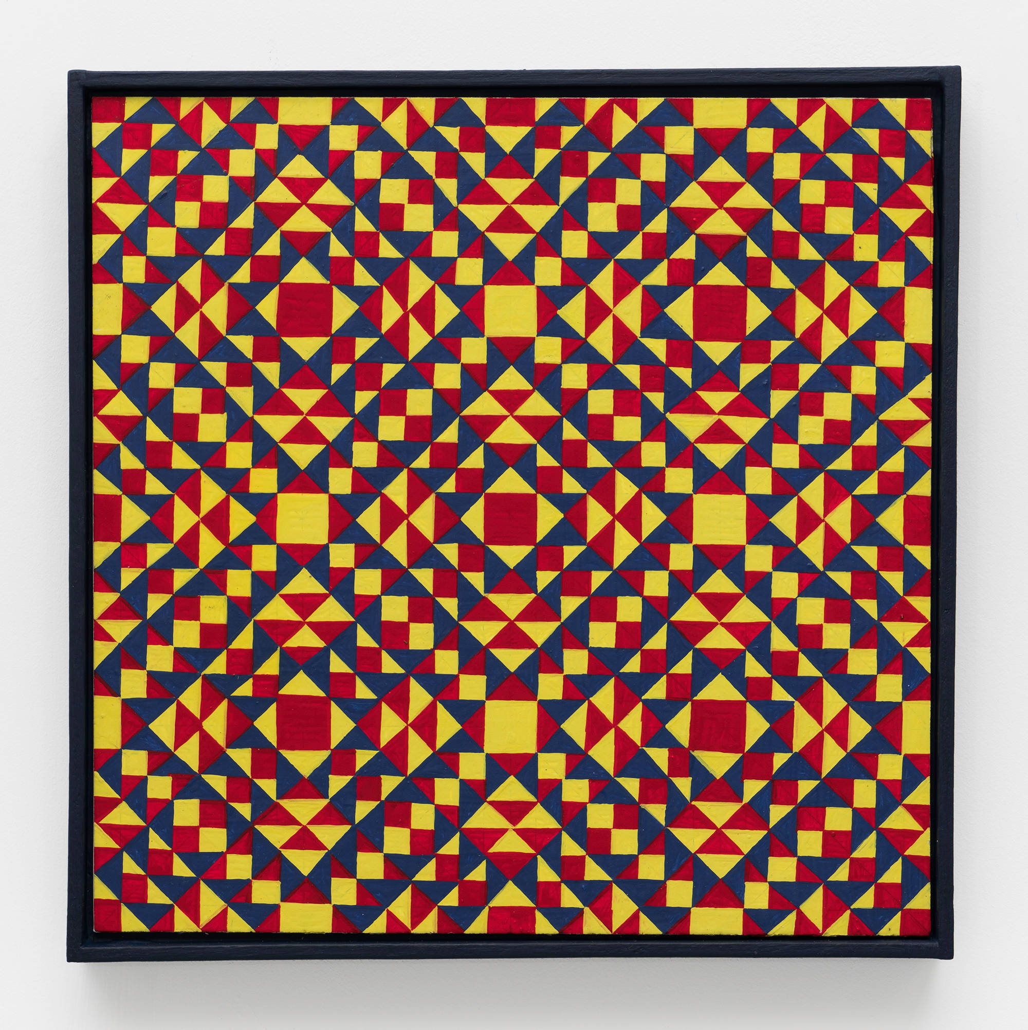 A colorful, symmetrical, geometric painting on board consisting of a pattern of repeating diamonds and triangles of red, yellow, and dark blue in a dark blue artist frame.