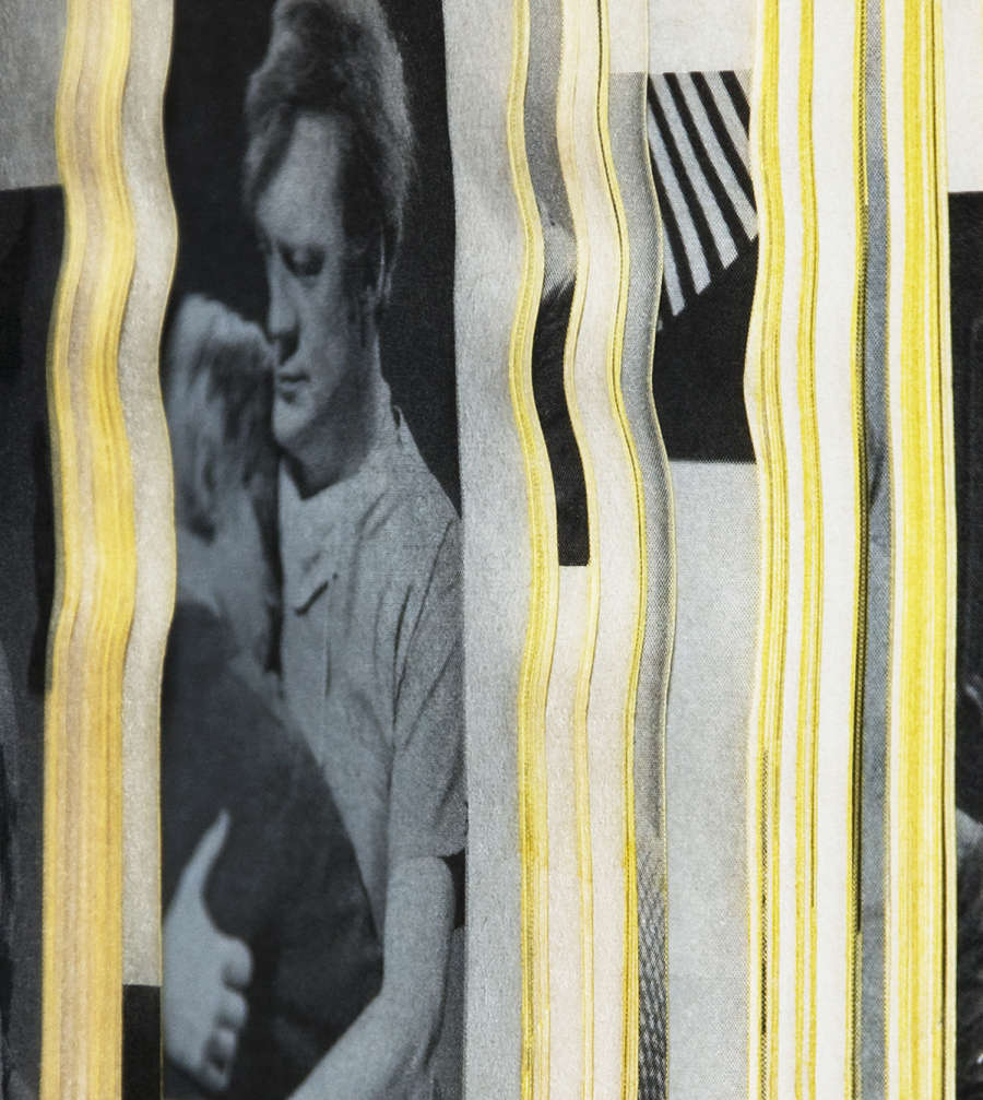 Photograph peering into an open book with the edges of the book's paper creating thin wavy vertical stripes resulting in an mostly abstract image of color and shape. Visible is a cropped image of a man embracing another person solemnly. All other strips are fairly unrecognizable. The image is mostly black and white except for the yellow dyed paper edges.