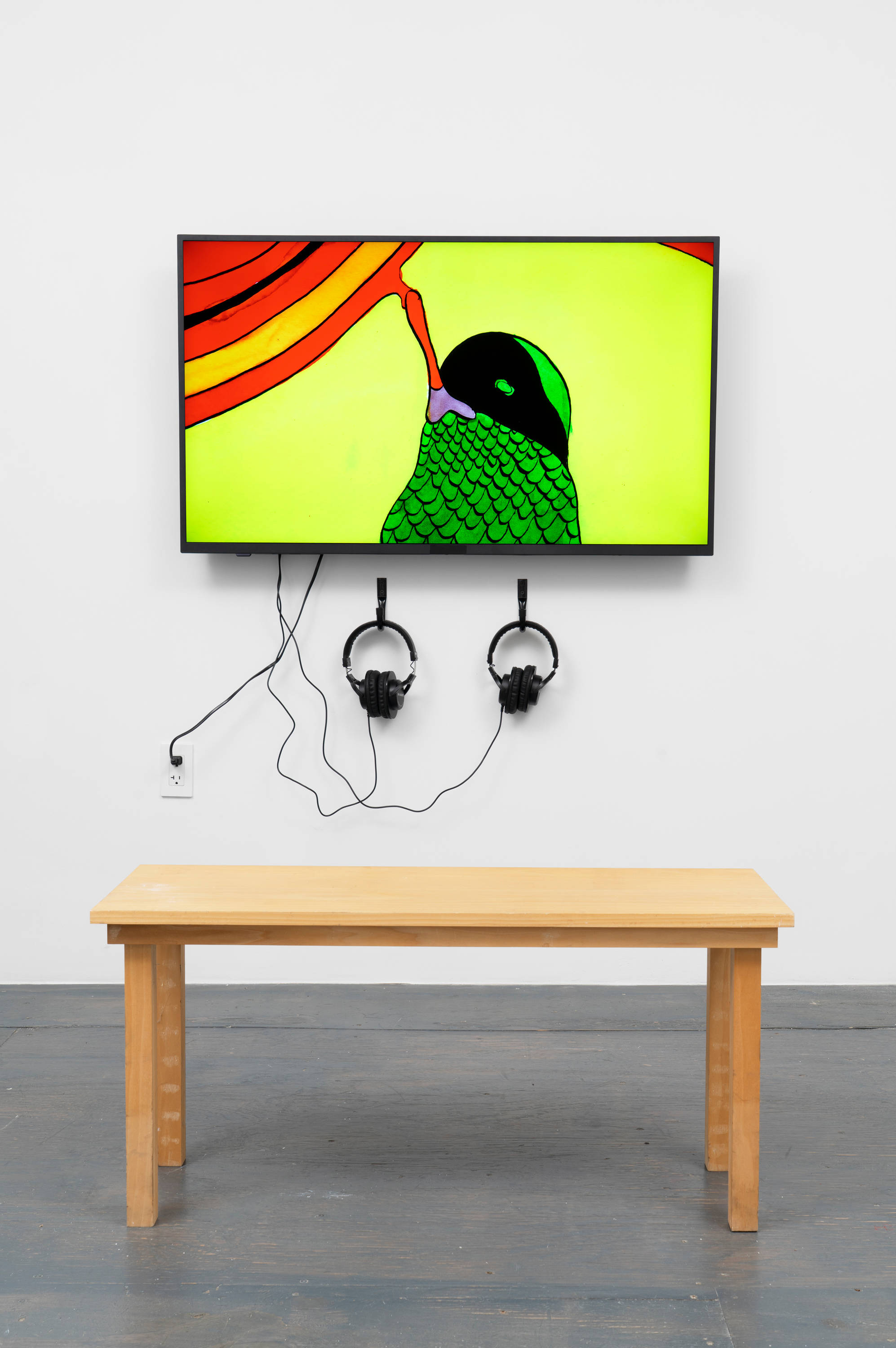 A monitor displaying Christine Rebet's film 'The Fall' hangs above a grey floor. Two pairs of headphones extend from the monitor. A wood bench sits in front of the monitor.