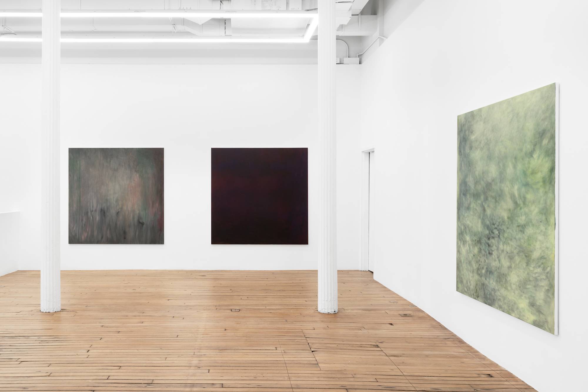 Three large abstract paintings full of gestural marks spaced evenly throughout a brightly lit gallery space.