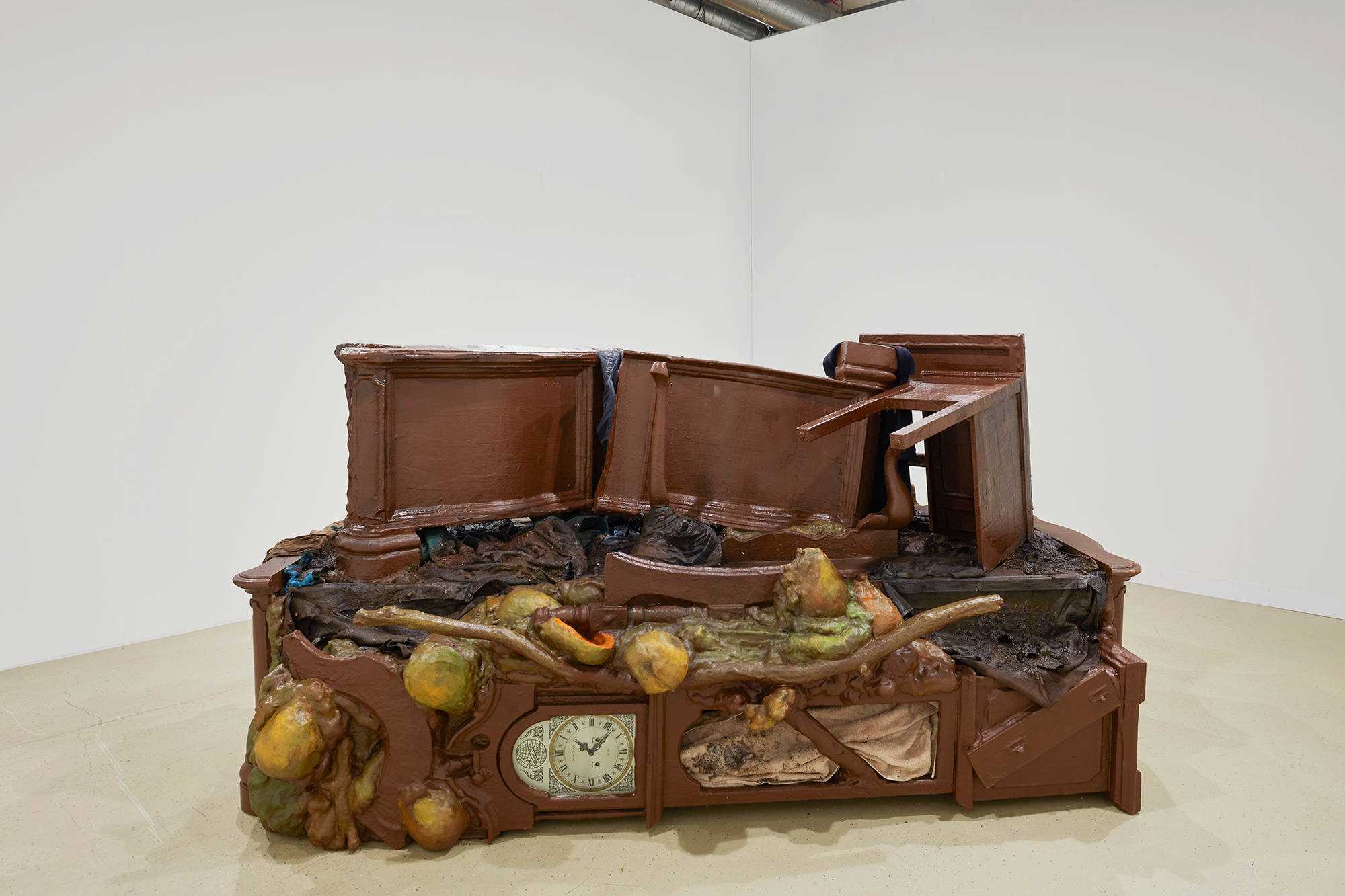 A large piece of brown furniture sits in the middle of a room with white walls.