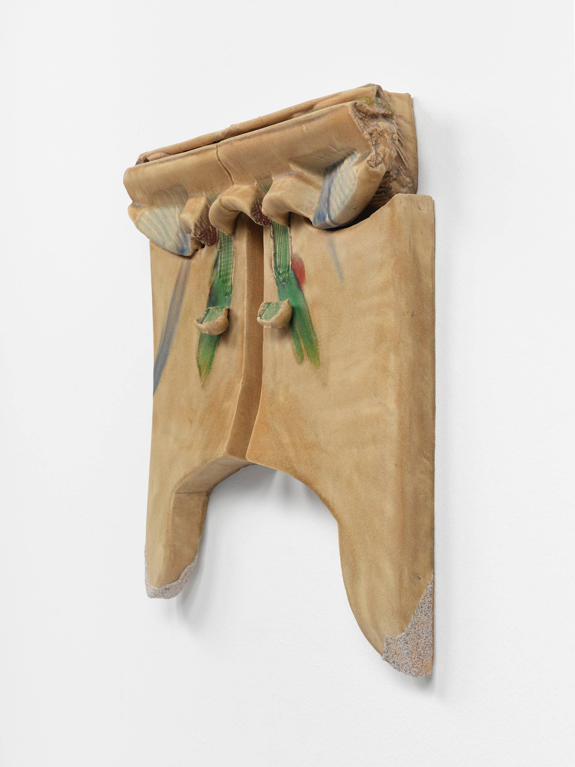Three quarter view of two ceramic sculptures hang on a wall mirroring each other with a thin channel dividing them. The clay has been pushed and stamped to create appendages near the upper edges that resemble small wings glazed faintly blue. Towards the center of the composition, both pieces have been gouged in a downward motion through the shoulder of the wings resulting in narrow vertical troughs that end in a small lifted flaps. A green glaze runs through the troughs and flaps. Each sculpture is tipped with a small peninsula still coated with sand from the kiln they were fired in.
