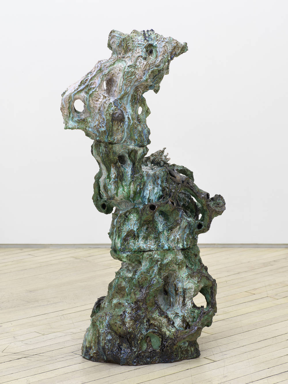 A freestanding, abstract ceramic sculpture resembling a figure merging from a landscape.
