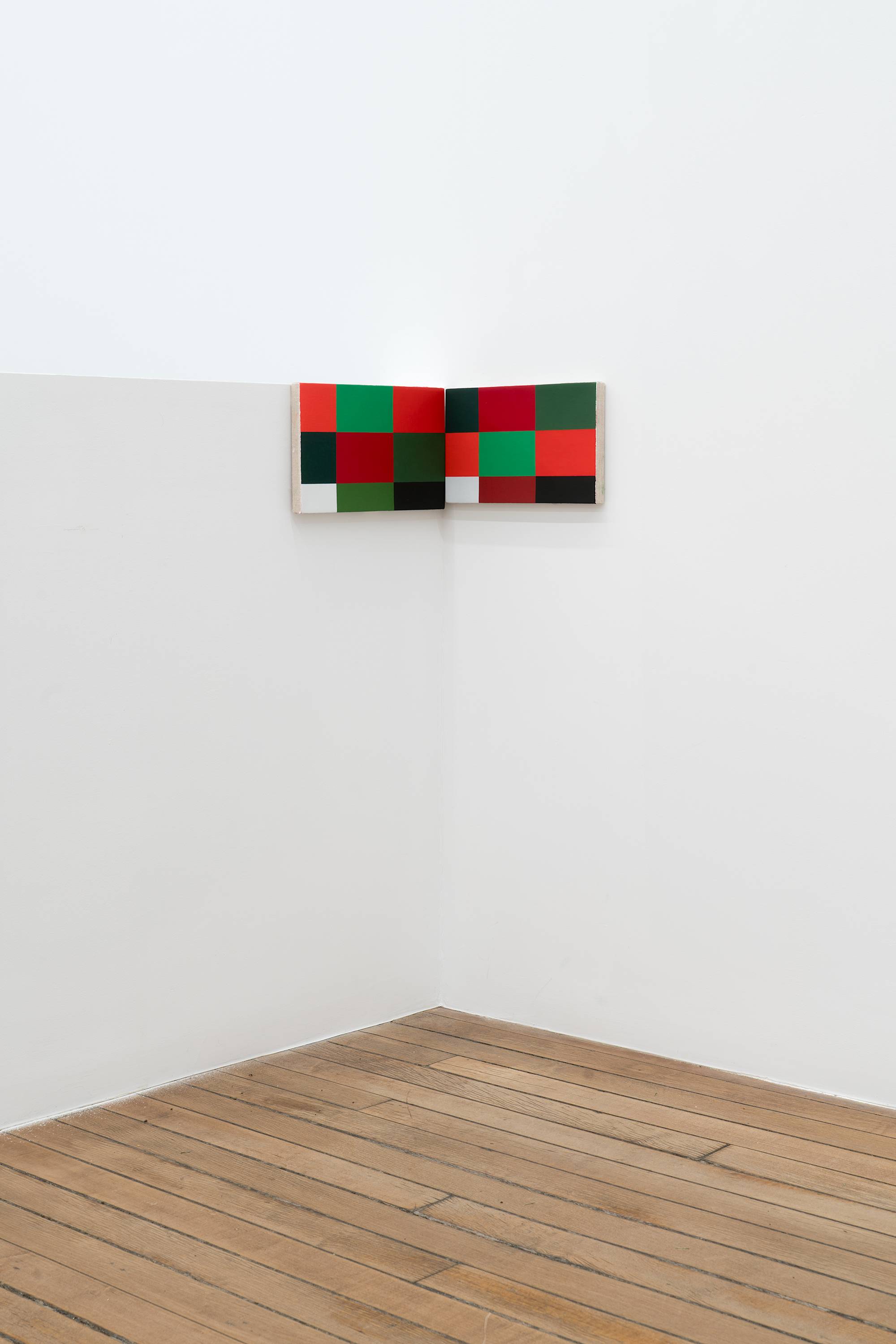 Two Ian Miyamura paintings of red, green, black and white squares hang in the corner of the gallery.
