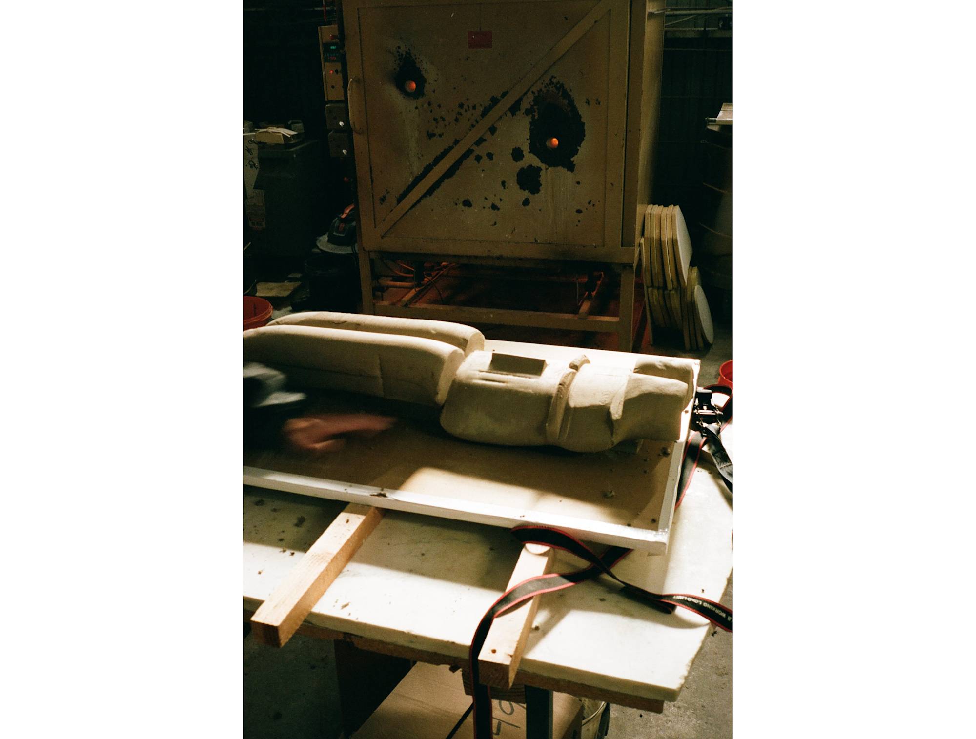 A film image of a ceramic artwork resting next to a firing kiln.