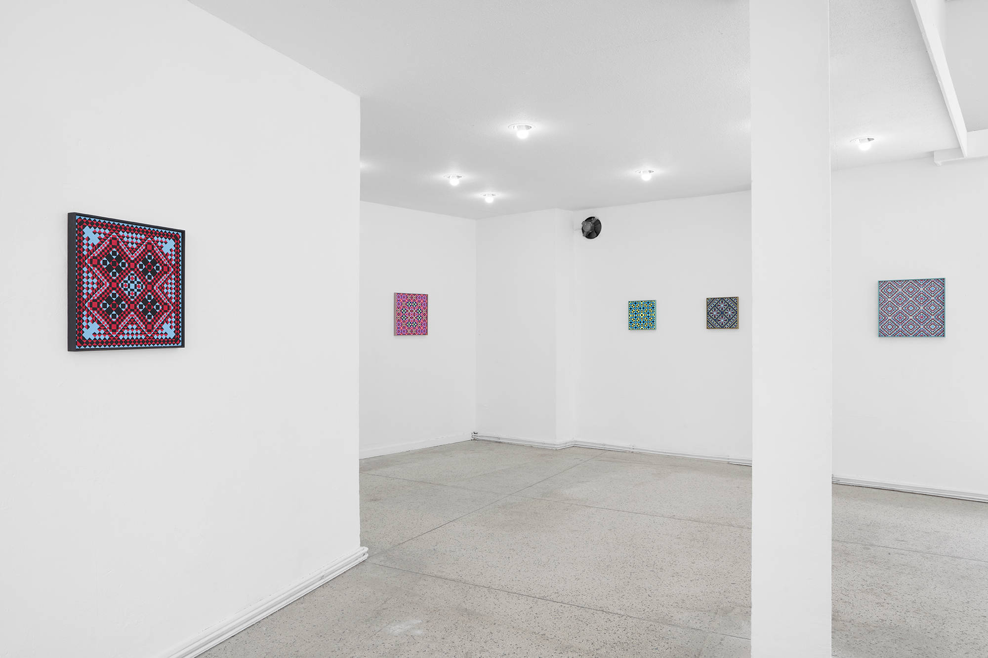 Image of a gallery space with five paintings installed. A pillar is on the right in the open space, and on the left, closest to the viewer, is a detailed grid painting.