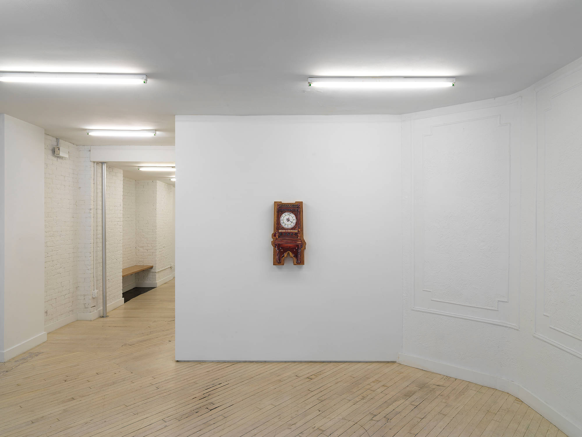 Image of a solo exhibition by Libby Rothfeld showing a shaped wooden panel with a realistic clock painted on the surface.
