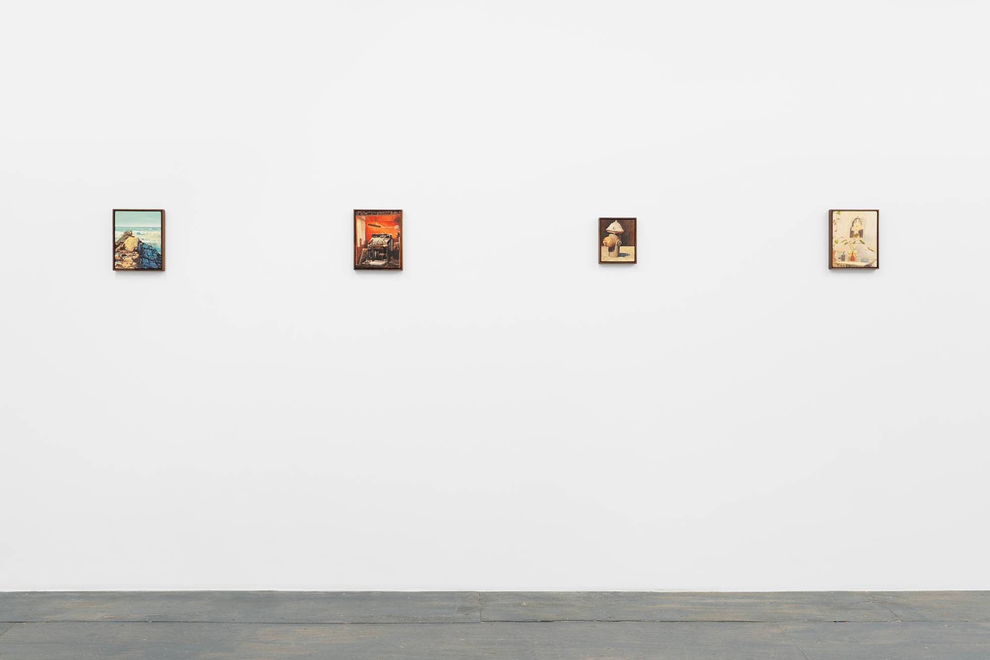 Four framed paintings are displayed in a line on a plain white wall, with a grey painted wood floor below. The artworks depict various scenes, including a seascape, an old cash register, a fire hydrant, and an apartment interior.