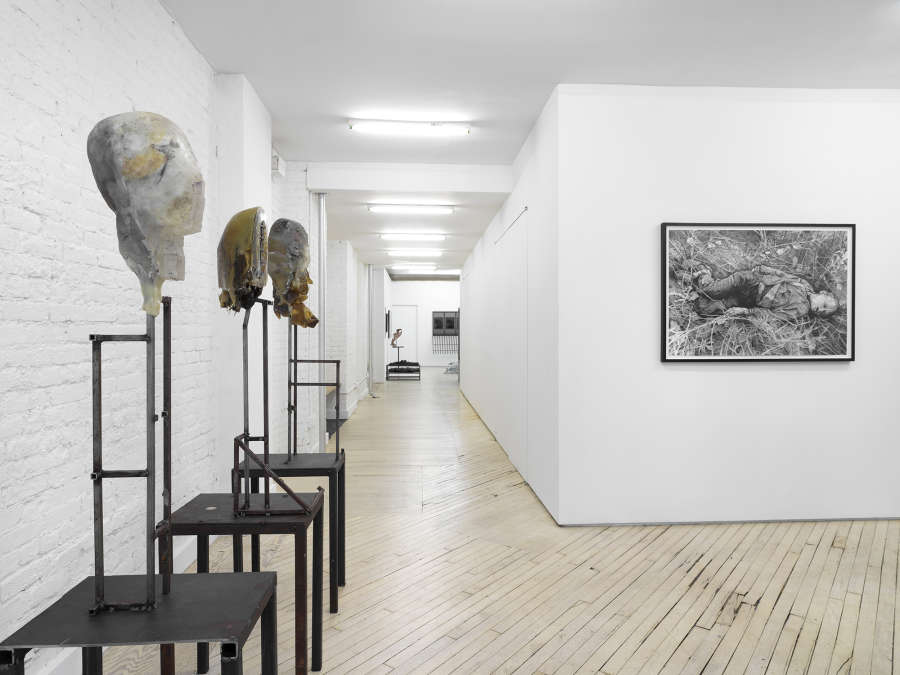 Several floor standing sculptures resembling mutilated human body parts on top of steel bases. On the back wall a graphite drawing resembling another human form in a black frame. In the back gallery are more related sculptures.