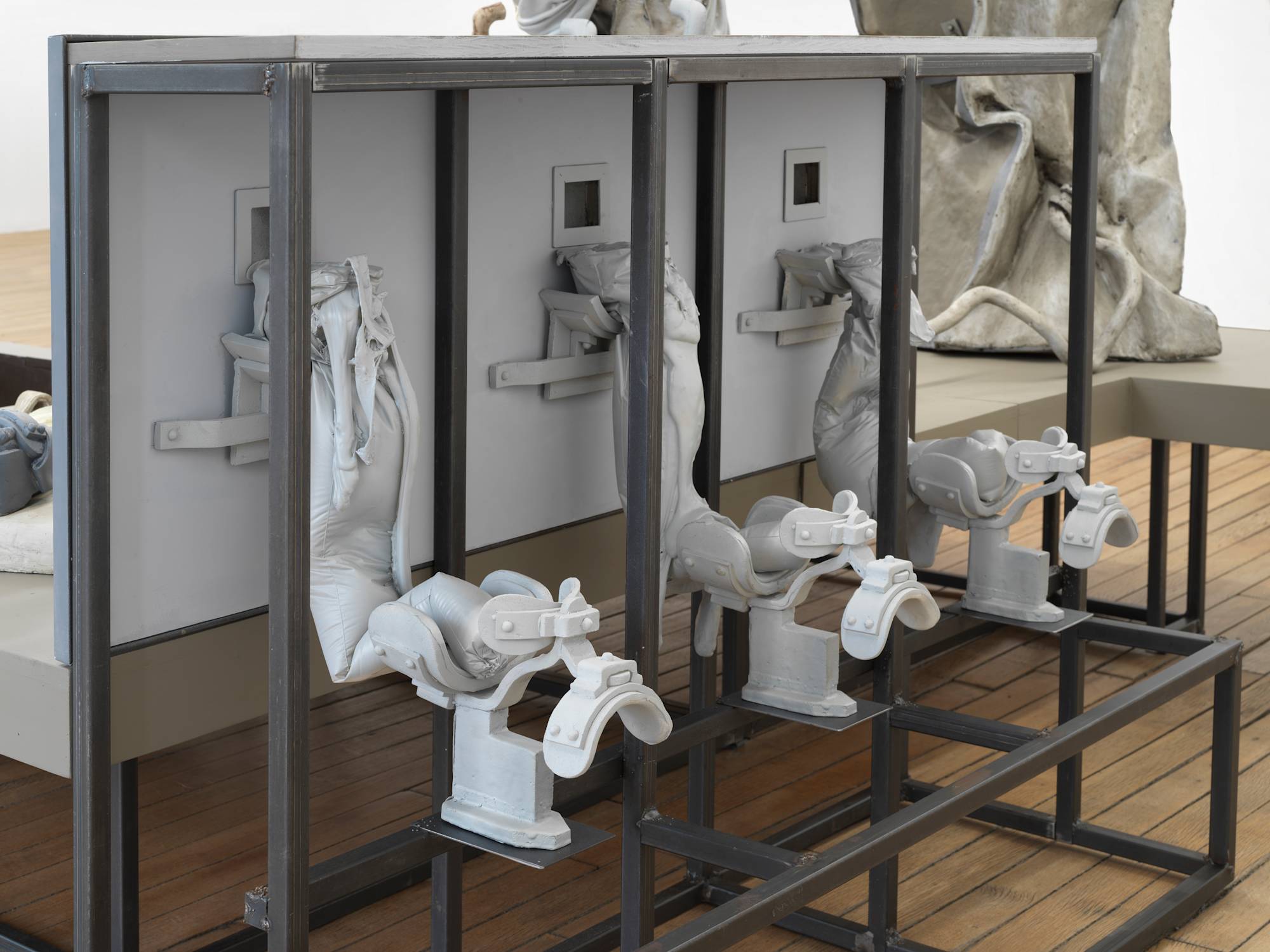 Close up image of a sculpture depicting abstracted human forms and structures resembling medical equipment.