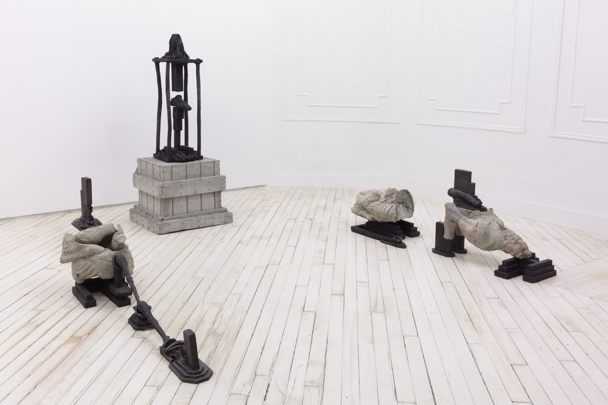Installation view of cast iron and concrete sculptures sitting on the floor.