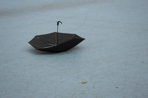 Image of an upside down black umbrella sitting on a concrete floor.