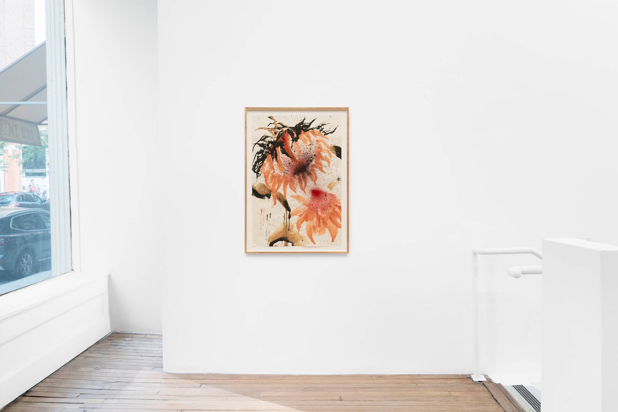 An ink painting of a cool orange and red sunflower with black leaves hangs in a white-walled gallery with a window and a wooden floor.
