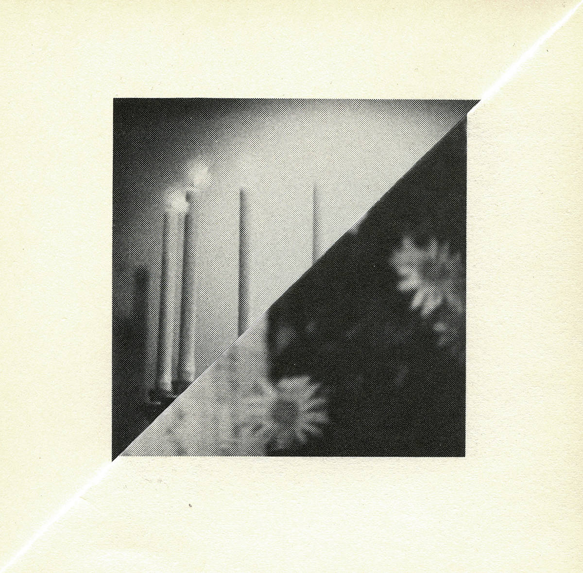 Image of the folded corner of the yellowed page of a book with a a central black and white square of imagery made of two triangles, showing candles and daisy flowers, which is the result of the folding of the page, and the internal images on the facing book pages.