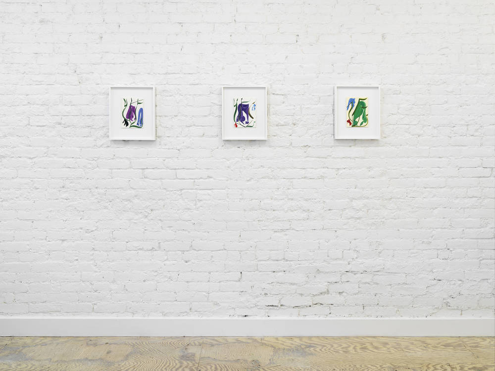 Image of three colorful paintings on paper by Patricia Treib, framed in white frames, hung sequentially on a white brick wall.