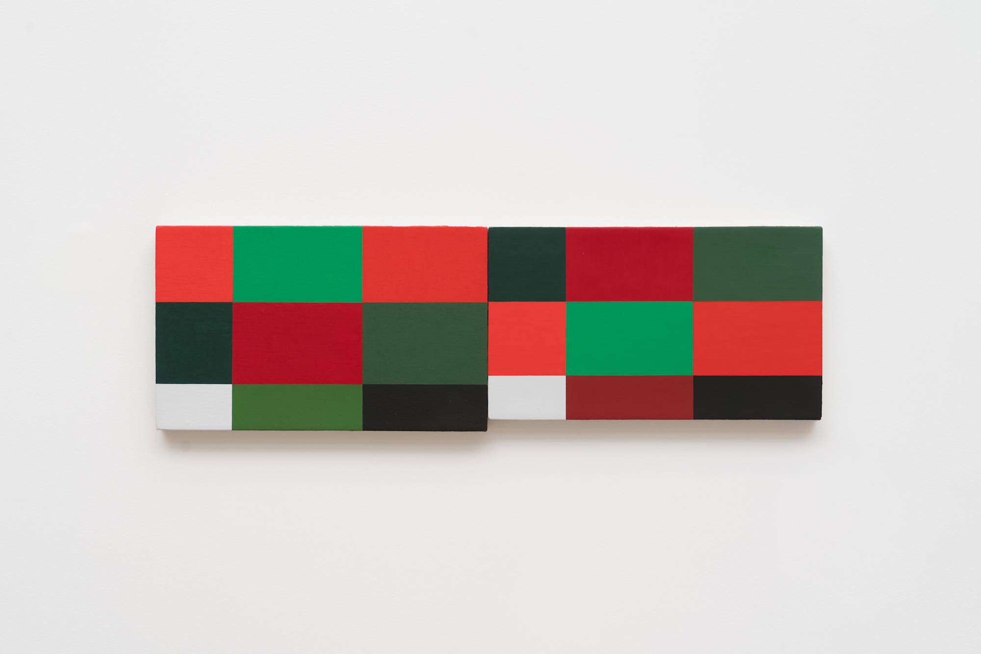 Two Ian Miyamura paintings of red, green, black and white squares hang on the wall butting against each other.