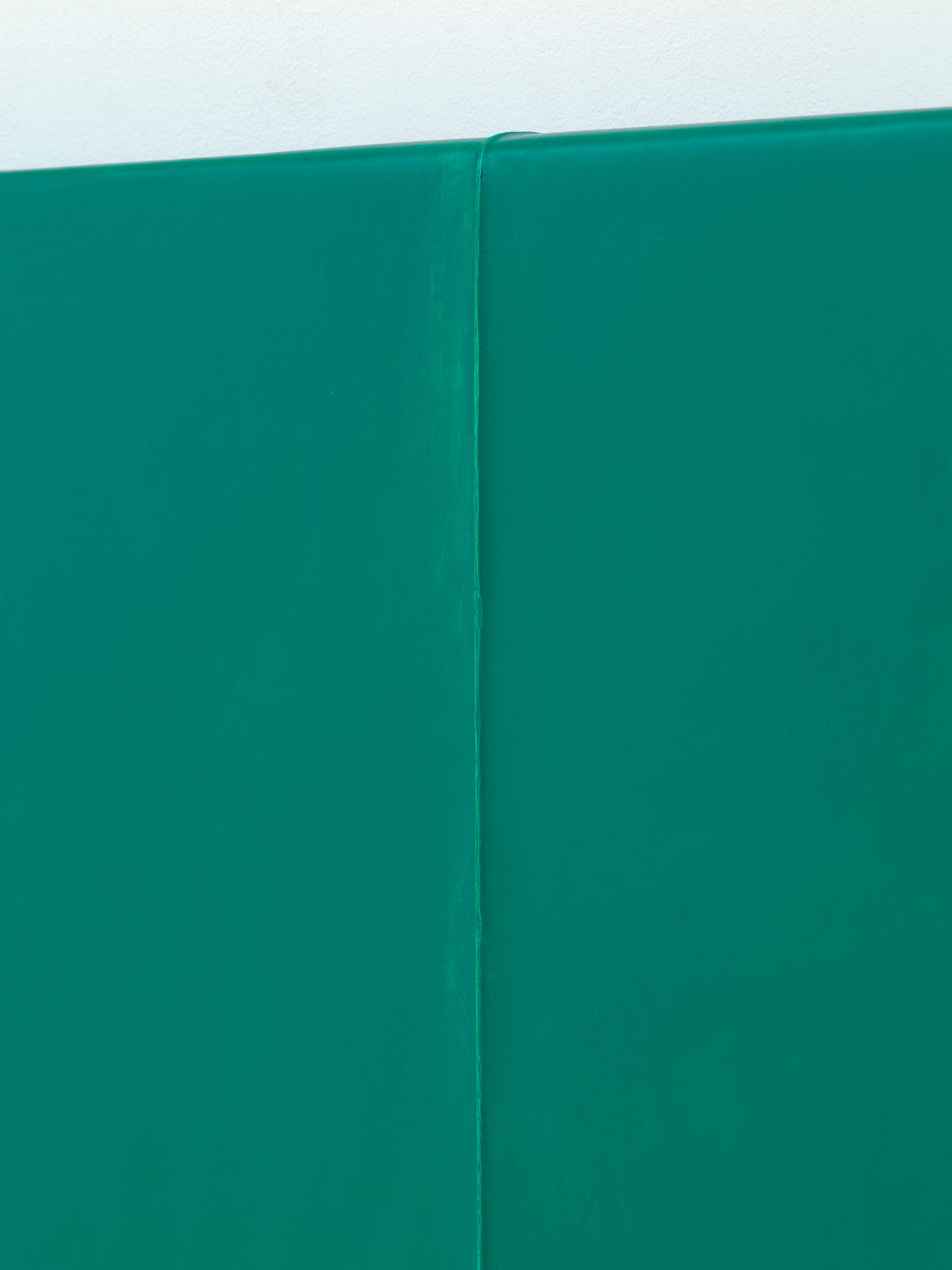 A close-up angle of a crease in a monochromatic green painting.