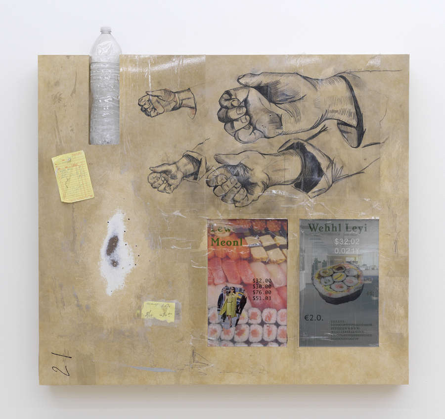On a white wall, a large abstract sculpture. The sculpture contains hand drawn images of a human hand. There is a yellow printed receipt on the left side. To the right is a printed image of sushi rolls. There is a water bottle inserted into the top left portion of sculpture.
