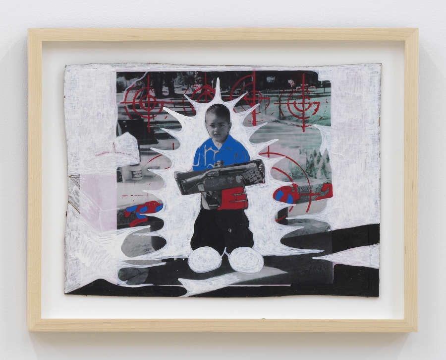 A small abstract drawing and collage with a cutout photograph of a young boy in the center. The drawing is in a wood frame. 