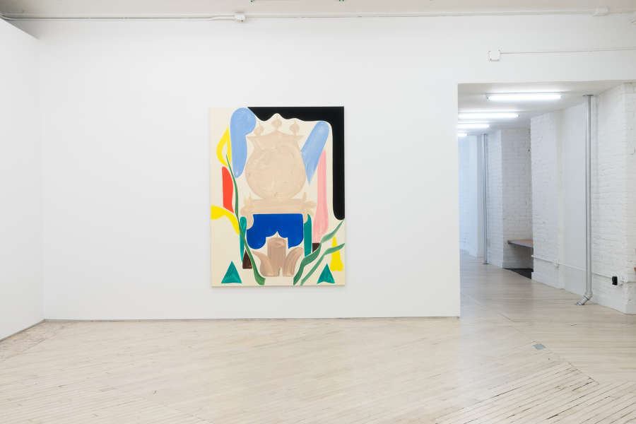 A large abstract painting in the center of a white wall. To the right of the painting is a hallway leading into another gallery space with a row of fluorescent lights. The painting contains a central pale brown abstract form. Surrounding the central form are other gestural marks painted in black, light blue, red, yellow, and green.