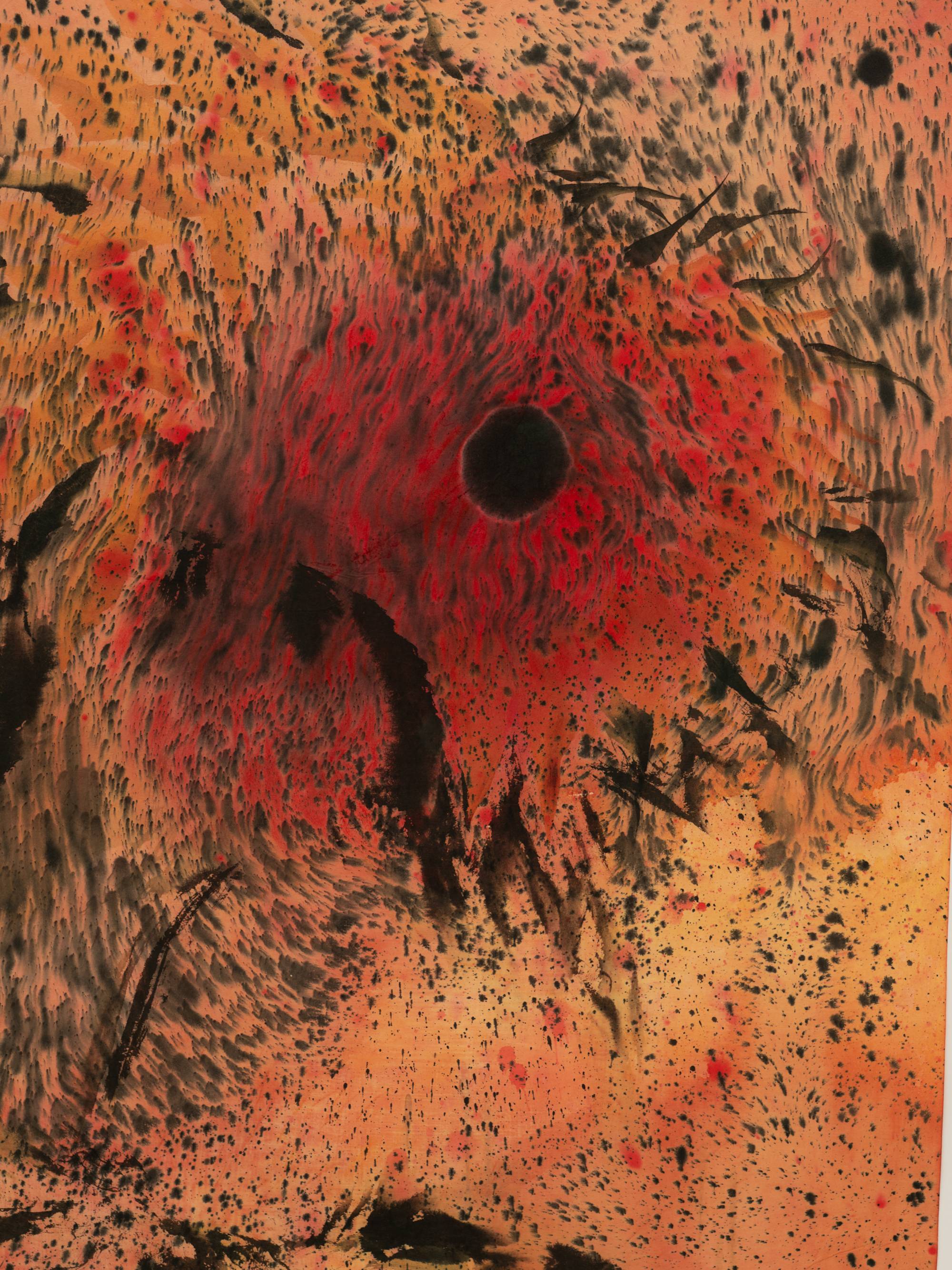 A vertically oriented close-up shot of an ink painting of two diffused sunflowers, with dark orange and black centers. Black speckles of ink swirl around the two heads of the sunflowers on a dark-orange and ochre background. The close-up focuses on the center of the two sunflowers and the black and orange speckles and streaks that surround them.