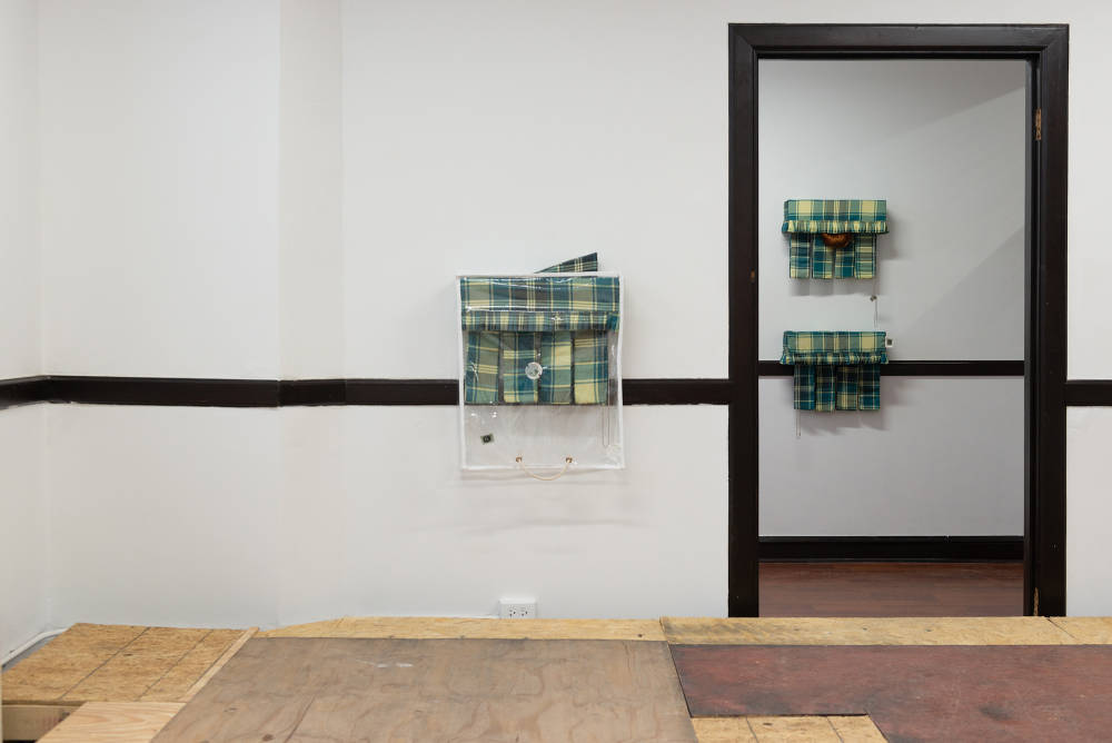 Three wall mounted sculptures resembling curtain composed of various fabrics. 
