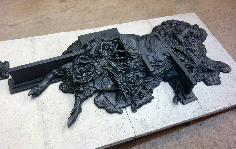 Installation view of metal and concrete ramp sculpture with cast iron sculpture on top resembling a decaying animal.