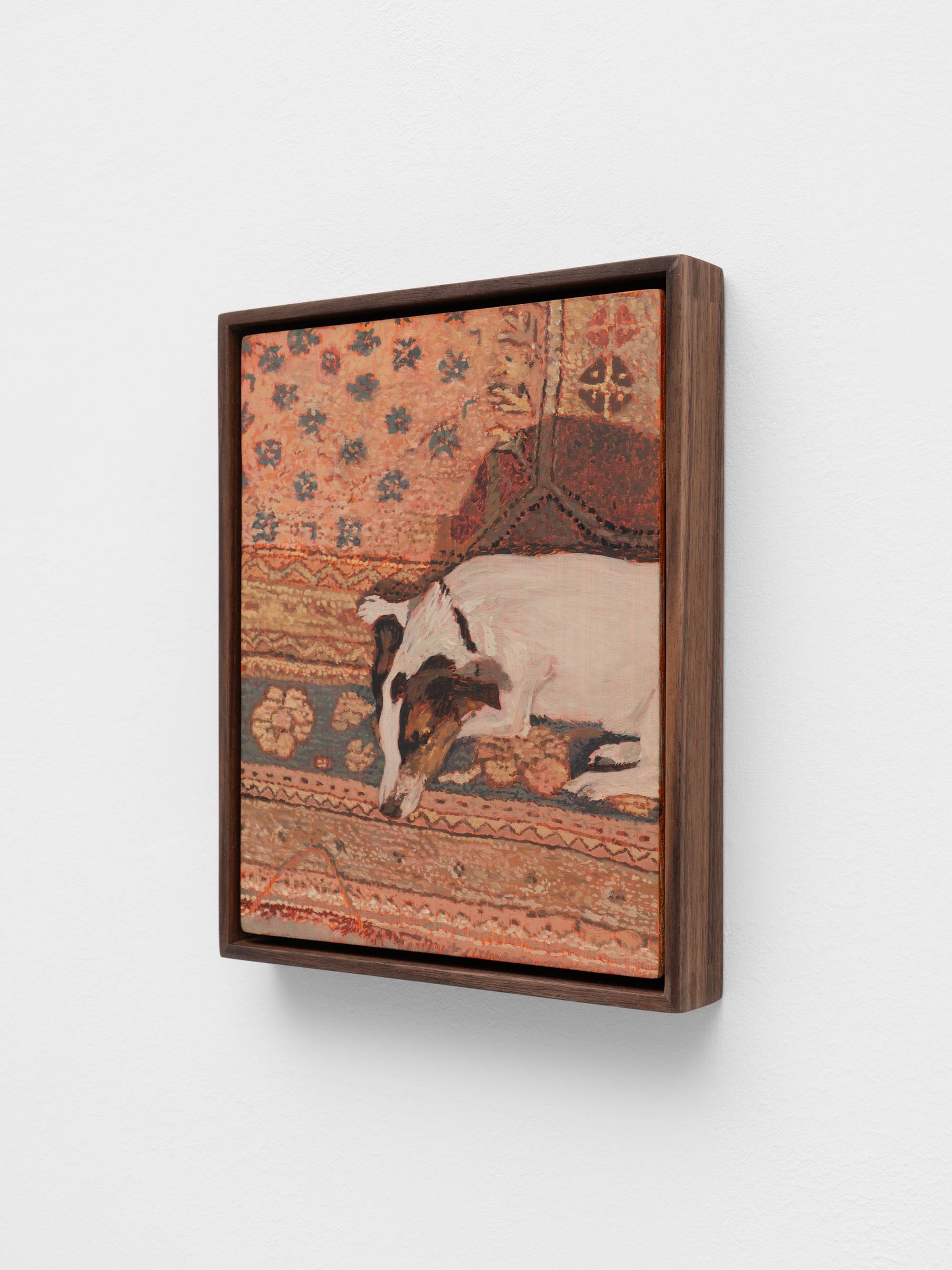 A painting framed in dark wood depicts a dog with white and brown markings lying on a patterned rug. The rug features floral motifs and geometric borders in shades of orange and blue.
