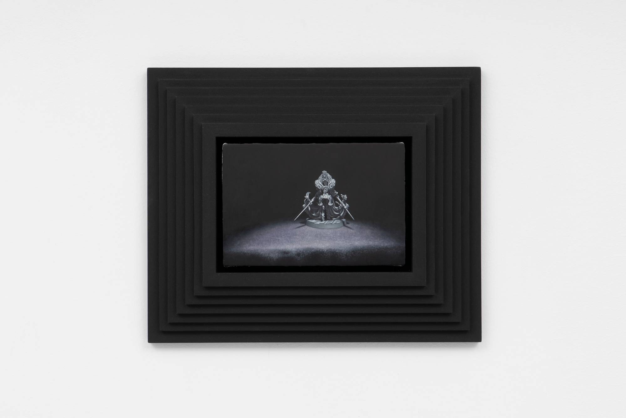 A painting featuring a warhammer model posed against a black background in a custom, black, tiered, pyramid frame fabricated by the artist.