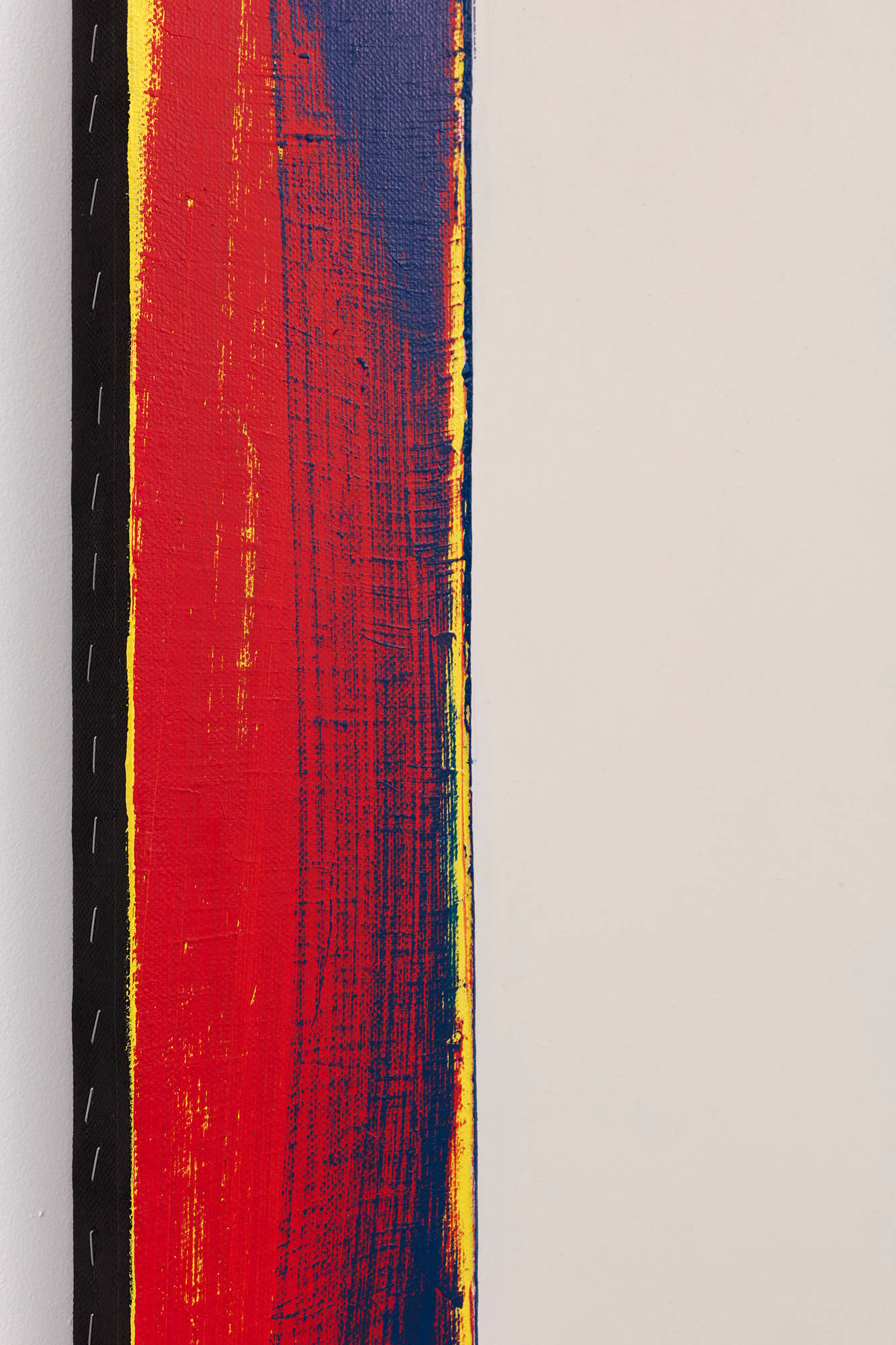 The side view of an abstract painting with a brushy red and purple side with a black edge and exposed staples.