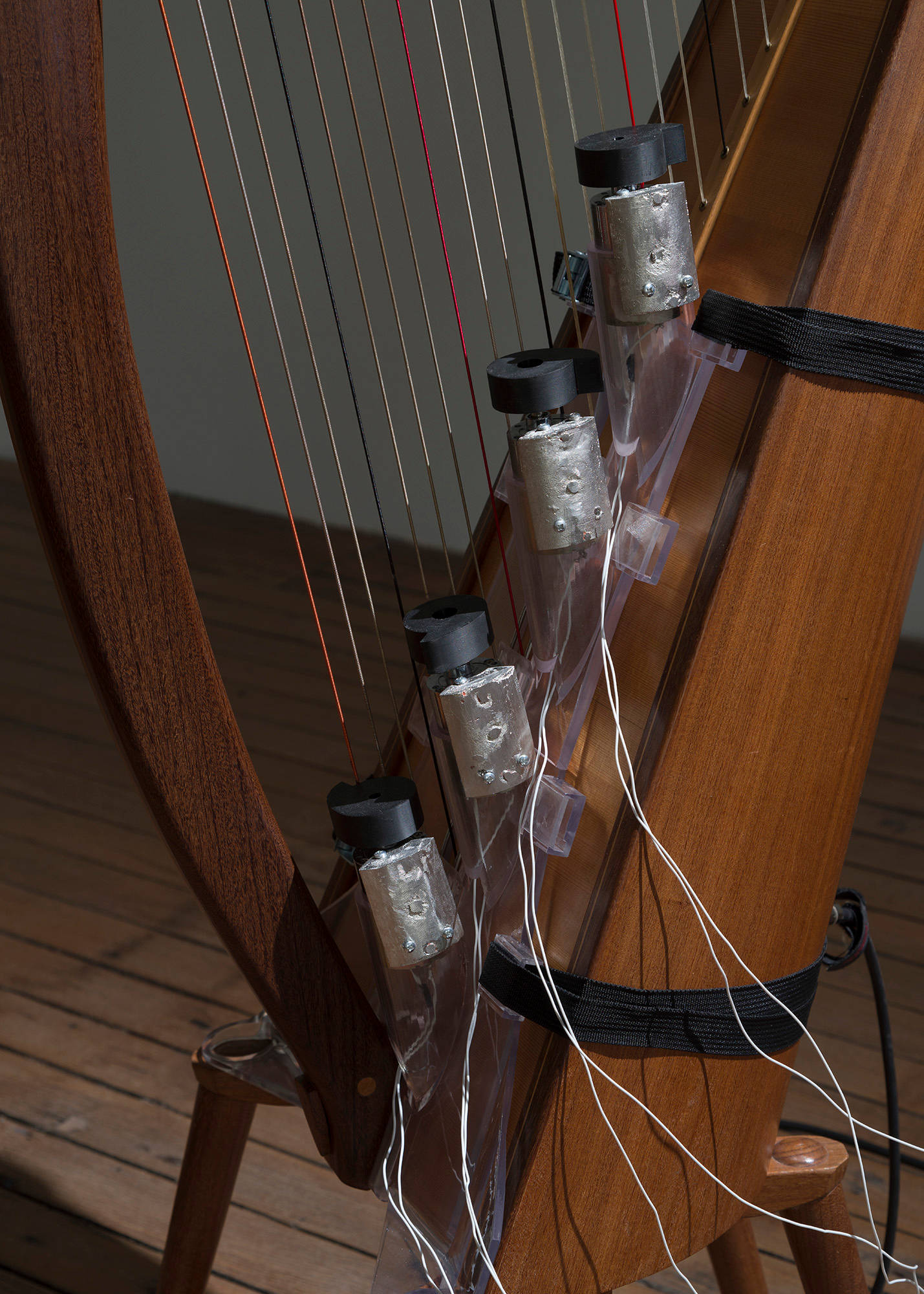 A close up image of motorized hammers strapped to a self-playing harp.