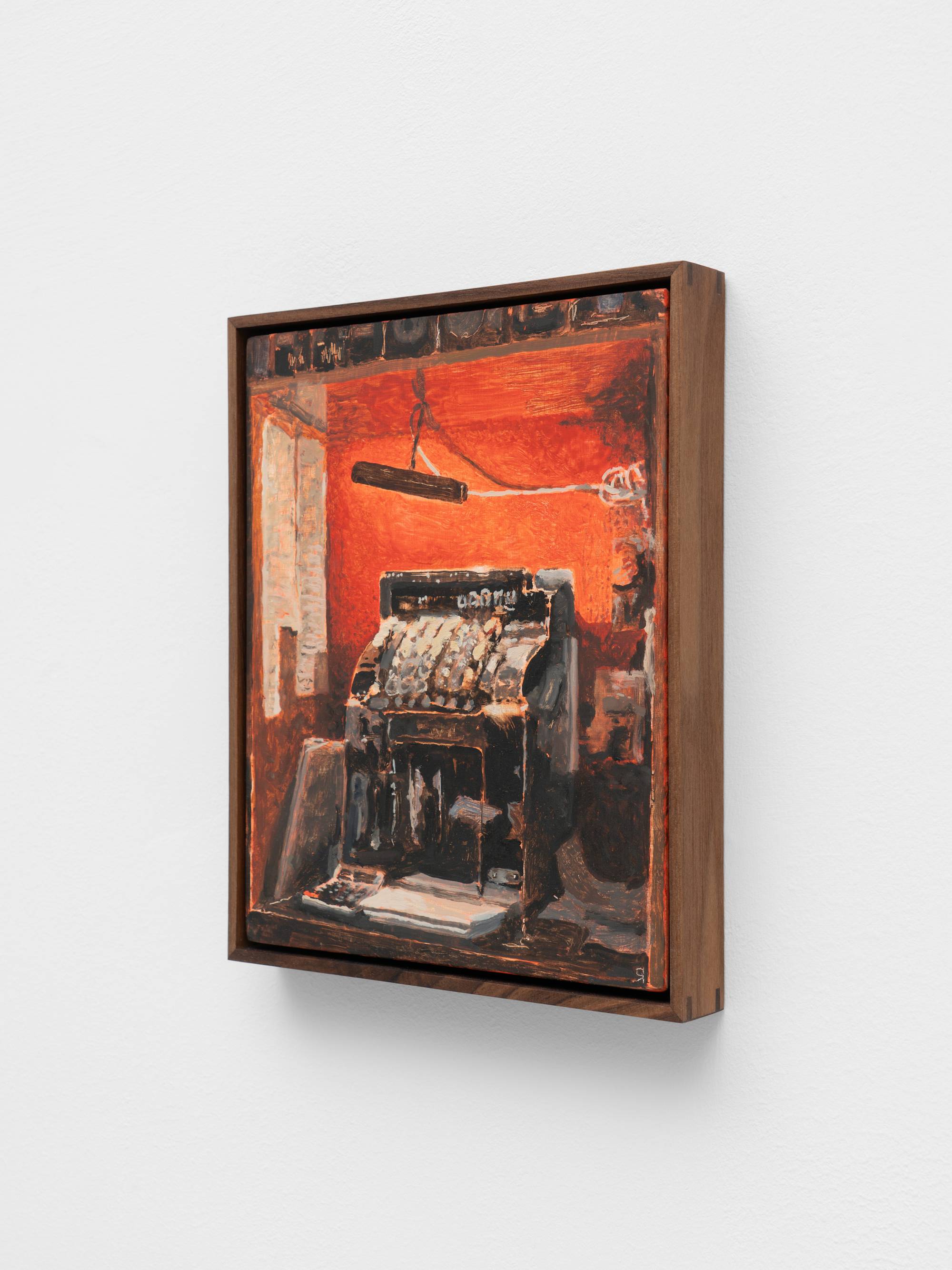 A small, dark wood framed painting of a cash register against a red wall.