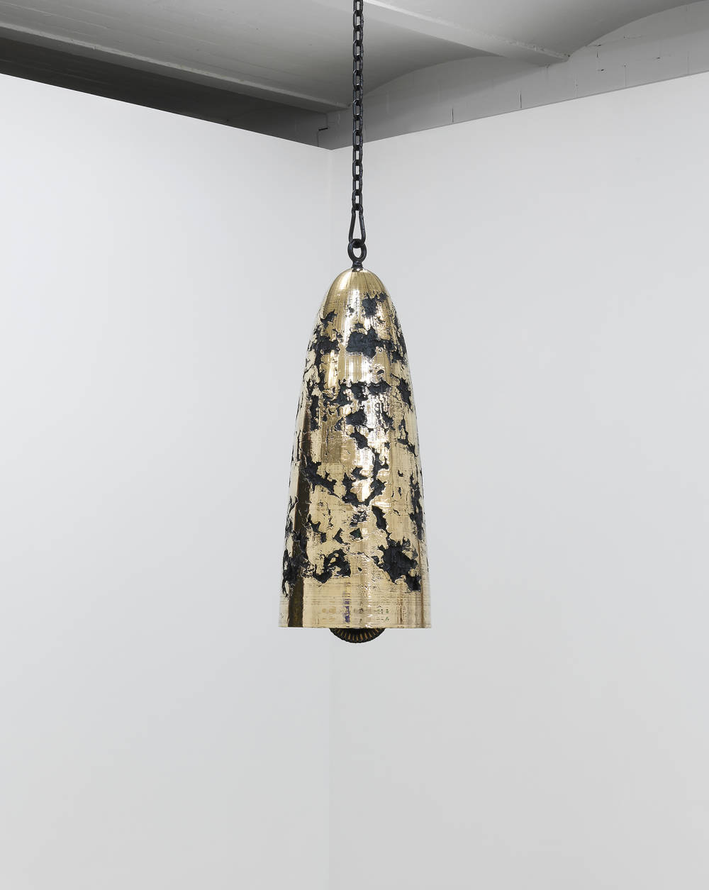 Image of a hanging bronze bell sculpture by Davina Semo, with a very reflective polished surface and dark textural pitting visible throughout