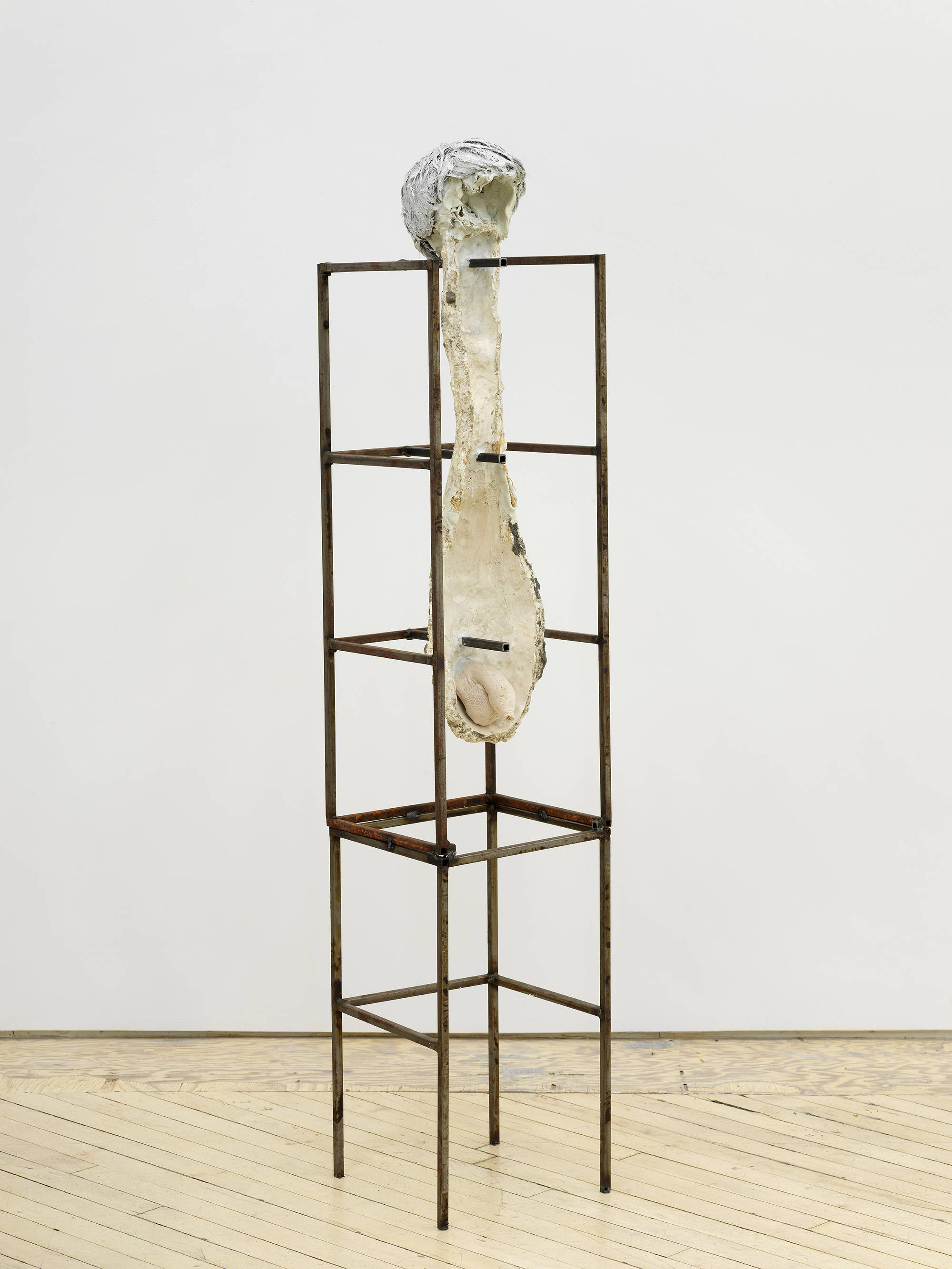 In a gallery space, an abstract sculpture resembling a human form with a steal base.