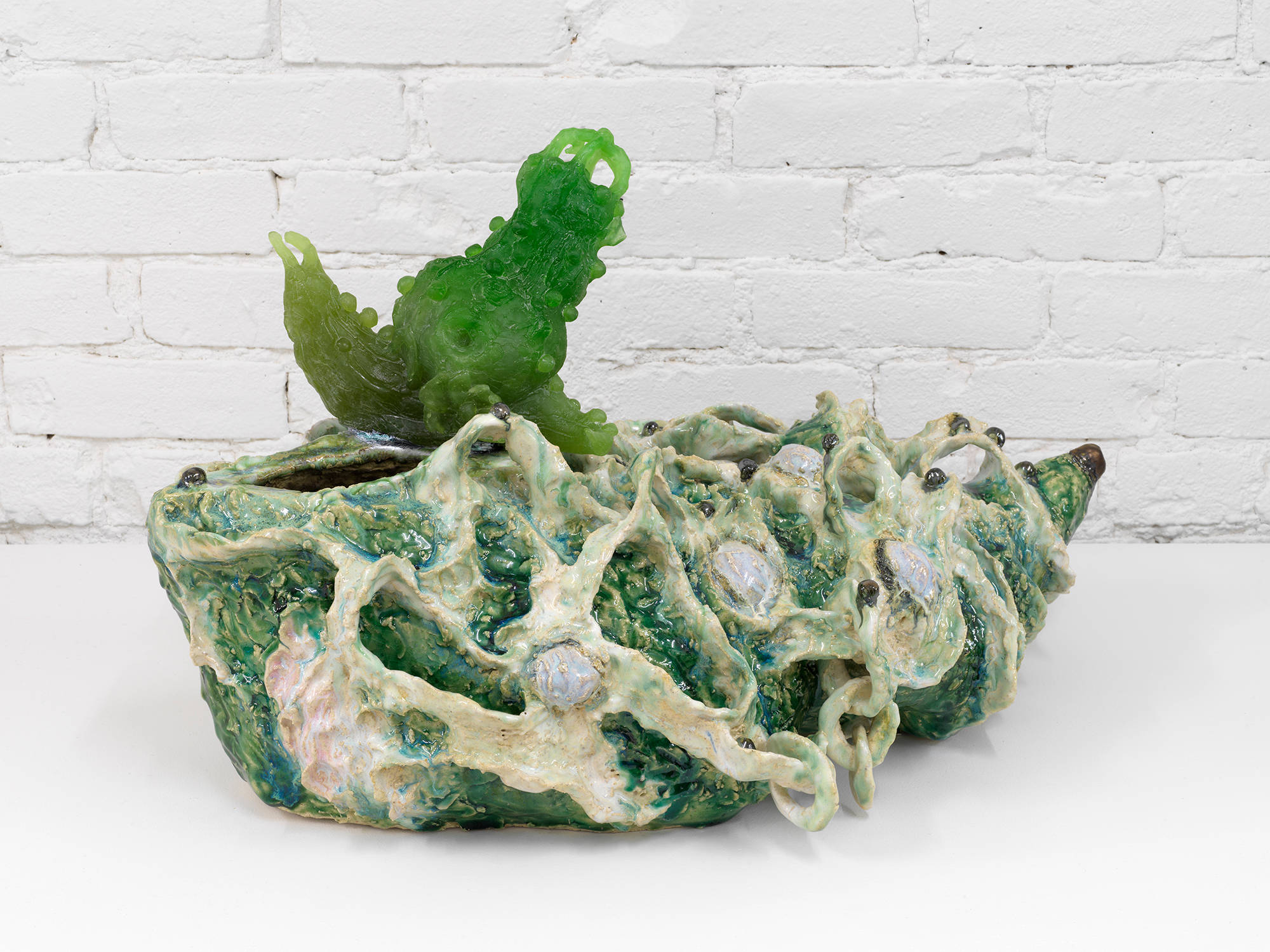 A freestanding, abstract ceramic sculpture resembling a landscape populated by different human and animal  forms.