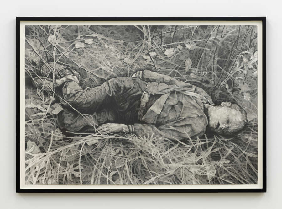 A framed graphite drawing of a small boy laying on the ground possibly dead.