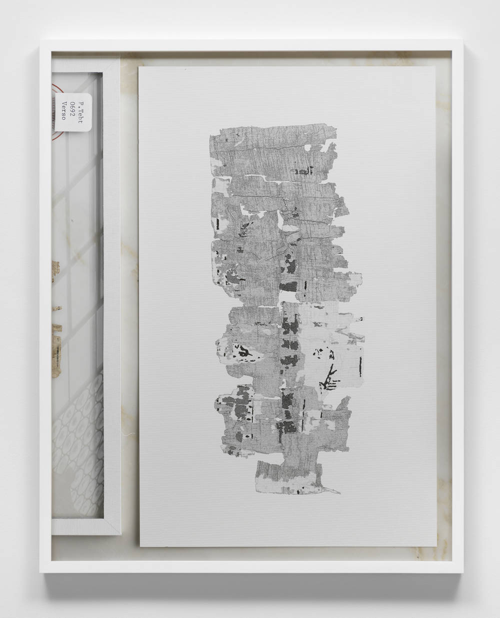 Image of a framed print by Jeffrey Stuker depicting a digitally rendered scene, shot from above, of a piece of papyrus and a drawing of the same papyrus on the right.