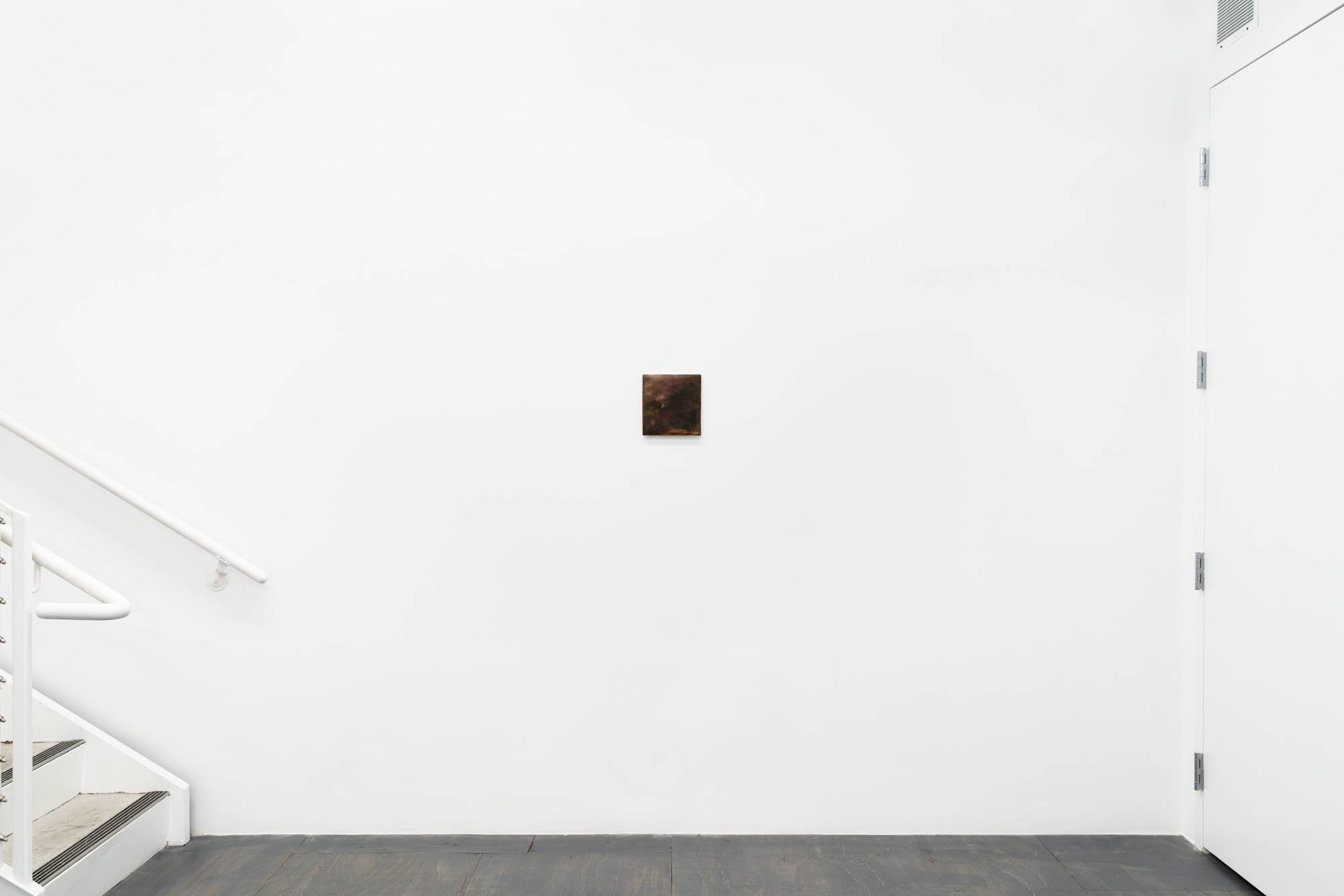 A small abstract painting of flowers hangs alone on the wall of a brightly lit gallery with grey floor. There is a door to the right, and stairs leading up and out of frame on the left.