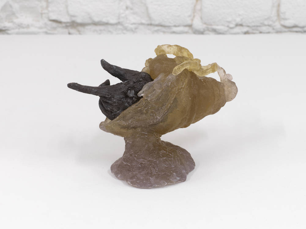 A small abstract ceramic sculpture resembling a hand emerging from another form. 
